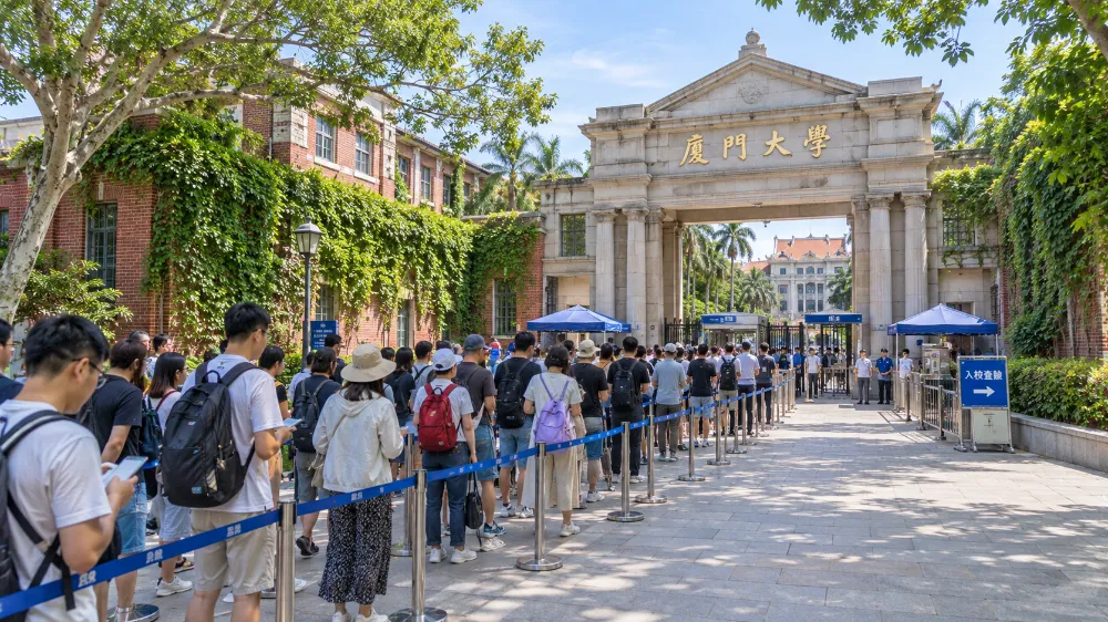 廈門大學校門前的通道,數十名旅客手持身分證排隊等待入校查驗,牆面爬滿綠藤 廈門大學校門前的通道,數十名旅客手持身分證排隊等待入校查驗,牆面爬滿綠藤